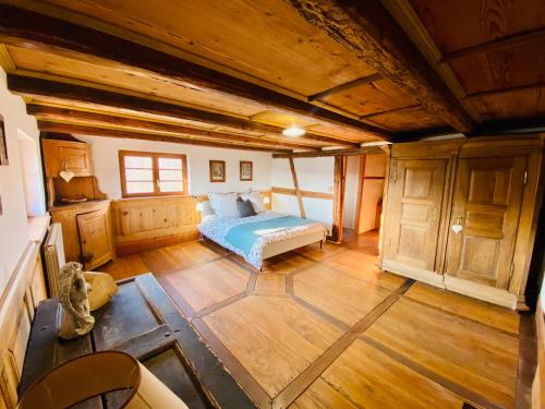 una camera con un letto in una stanza con pavimenti in legno di Gîte Le Chut - Piscine chauffée - 11 à 14 personnes a Rangen