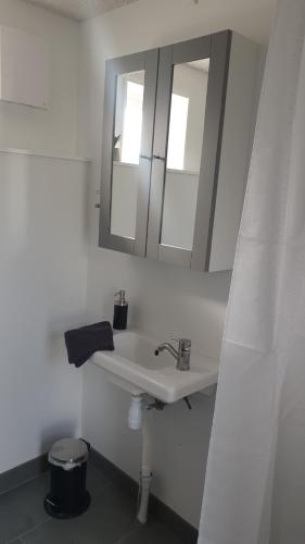 a white bathroom with a sink and a mirror at Cottages by the Sea in Sørvágur