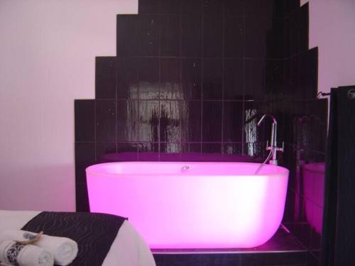 a pink bath tub in a bathroom with black tiles at Gite du Chateau in Éclassan