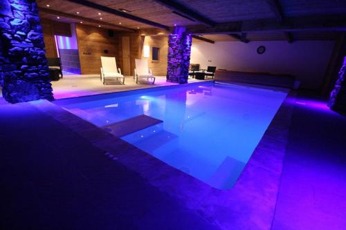 uma grande piscina com luzes roxas num quarto em Chalet Camillou em Champagny-en-Vanoise