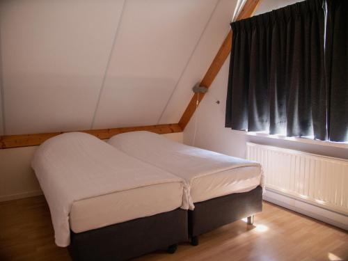 a small bed in a room with a window at De Sloothaak in Giethoorn