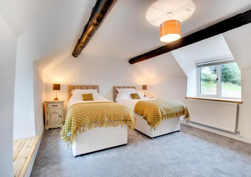 a attic bedroom with two beds and a window at Maerdy Uchaf in Gwyddelwern