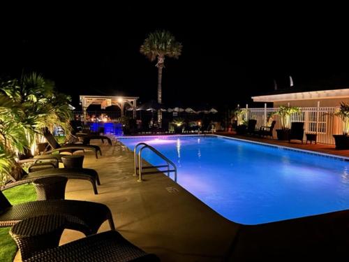 a swimming pool at night with chairs around it at Bleu Beach Resort in Indialantic