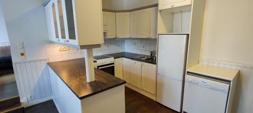 une cuisine avec des armoires blanches et un réfrigérateur blanc dans l'établissement Kirstulan Kartanon päärakennuksen upea päätyhuoneisto, à Hämeenlinna