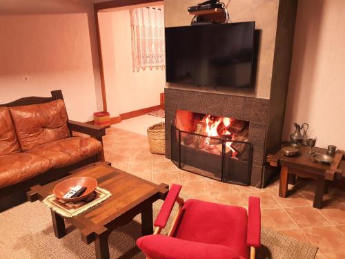 a living room with a fireplace with a television at Cabana Rústica - Sitio Kayalami in Tijucas do Sul