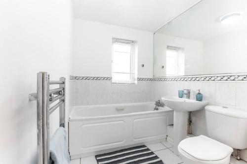a white bathroom with a tub and a toilet and a sink at Citrine - 2 Bed Apartment With Parking in Reading