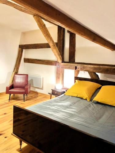 um quarto com uma cama grande e uma cadeira em Maison à colombage garage bureau centre village em Francescas