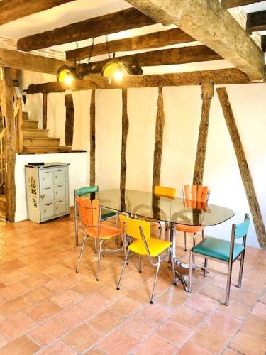 une salle à manger avec une table et des chaises en verre dans l'établissement Maison à colombage garage bureau centre village, à Francescas