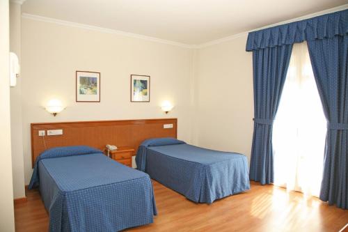 a room with two beds and a window at Hotel Peña de Arcos in Arcos de la Frontera