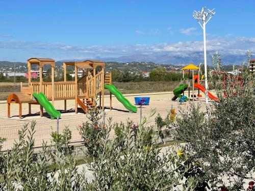 een speeltuin met glijbanen en schommels in een park bij Kronos Hotel in Durrës