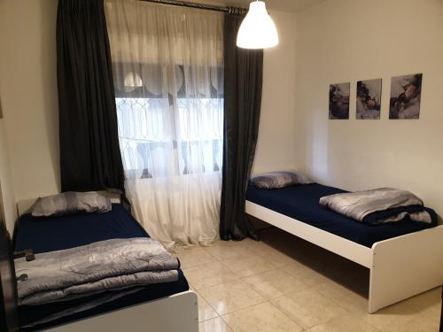 a bedroom with two beds in front of a window at Dair Ghbar 2-bedrooms unit in Amman