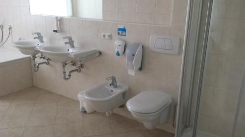 a bathroom with two sinks and a toilet and a shower at Manzoni Rooms in Merano