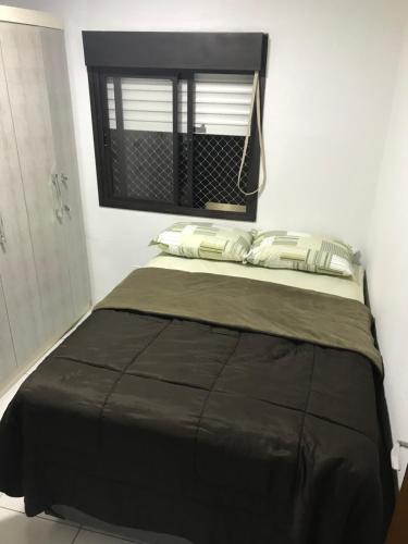 Bett in einem weißen Zimmer mit Fenster in der Unterkunft Apartamento encantador em bairro Nobre. in Santa Cruz do Sul