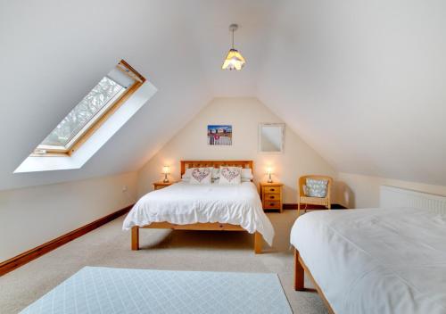 een slaapkamer op zolder met 2 bedden en een raam bij Nant y Llyn in Bala