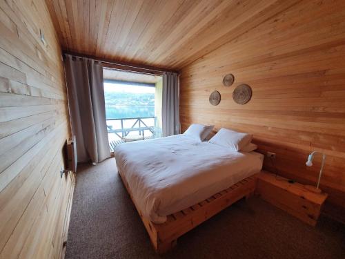 Cama en habitación de madera con ventana en Hotel & Café Bauda, en Castro