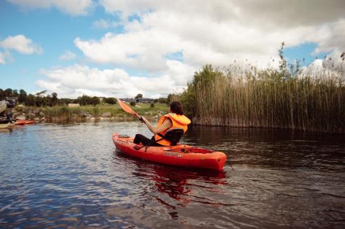 a woman is paddling a kayak on a river at Glasson Lakehouse in Athlone