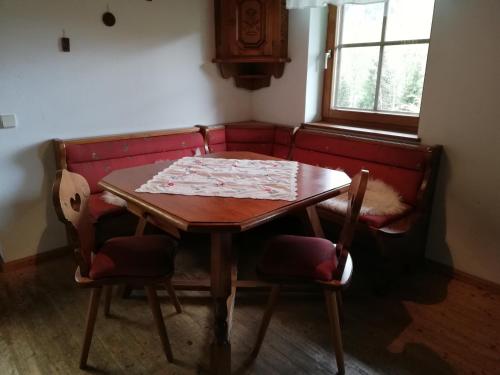 a dining room table and chairs with a red couch at Grundnerhof in Arriach