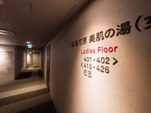 a wall with a sign on the wall of a room at Super Hotel Premier Ikebukuro Natural Hot Spring in Tokyo