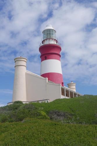 a red and white lighthouse on top of a hill at C-Pampoentjie in Struisbaai