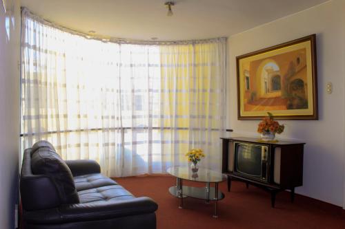 ein Wohnzimmer mit einem Sofa und einem TV in der Unterkunft Hotel San Felipe Suites in Arequipa