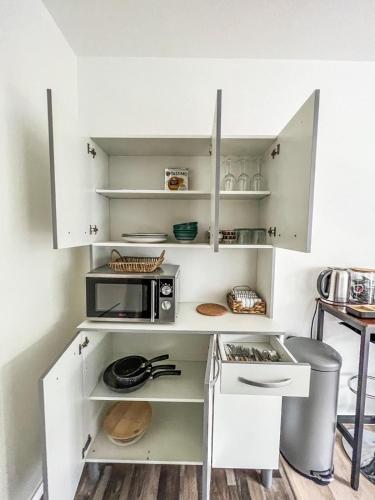 une cuisine avec des armoires blanches et un micro-ondes dans l'établissement RANGUEIL - Studio confortable proche hôpital et université, à Toulouse