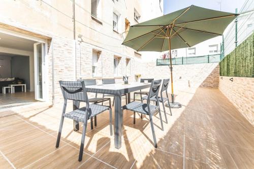 a table with chairs and an umbrella on a patio at Apartamento Balbín II in Gijón