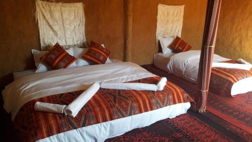 two twin beds in a room with at SaharaTime Camp in Adrouine