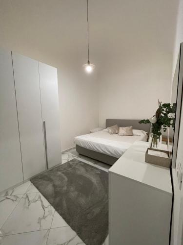 a small white room with a bed and a table at Affitta camere Tra mari e monti in Cecina