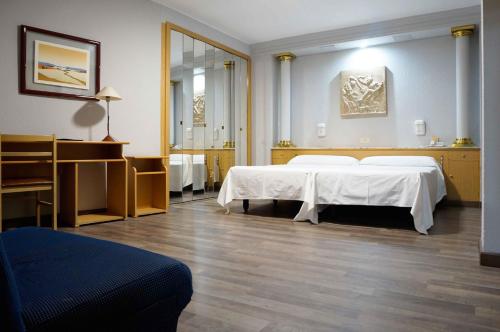 サラゴサにあるCesaraugustaのベッド2台と鏡が備わるホテルルームです。