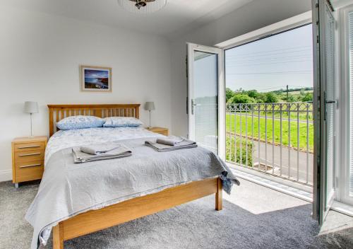 a bedroom with a bed and a balcony at Llety Celyn - The Hollies in Cross Hands