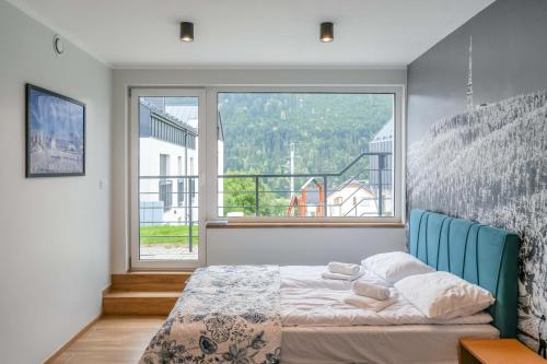 a bedroom with a bed and a large window at Apartamenty Słoneczna Góra w spokojnej okolicy - Dream Apart in Szczyrk