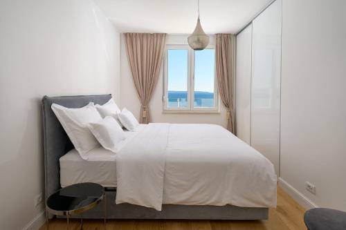 a bedroom with a white bed with a window at Klara Beach Apartment in Split