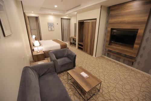 a hotel room with a couch and a bed and a television at Broad Almkan Apart Hotel in Taif