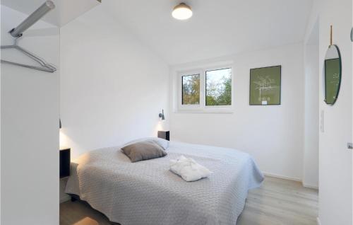 a white bedroom with a bed and two windows at Awesome Home In Lembruch-dmmer See With Sauna in Lembruch
