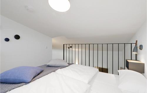 a bedroom with a bed with white sheets and blue pillows at Nice Home In Lembruchdümmer See in Lembruch