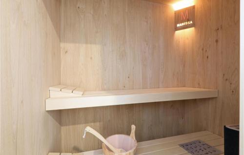a small kitchen with wooden walls and a shelf at Nice Home In Lembruchdümmer See in Lembruch
