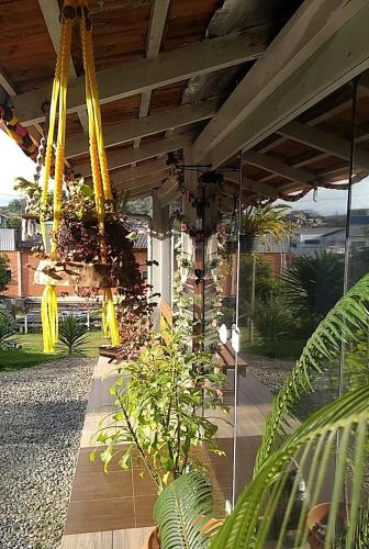 a patio with a wooden table with plants and yellow swings at Harmonia Haus in Blumenau
