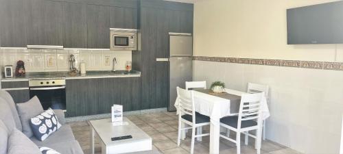 a living room with a table and chairs and a kitchen at APARTAMENTOS TURÍSTICOS CASA SANDRA in Sanxenxo