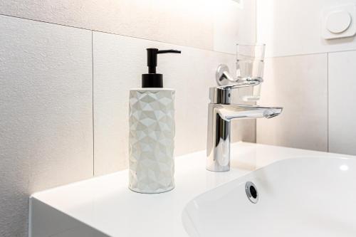a white bathroom sink with a soap dispenser on it at Landhotel Gutshof in Hartenstein
