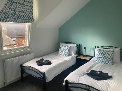 two twin beds in a room with a window at Printer's Apartment in Pontefract