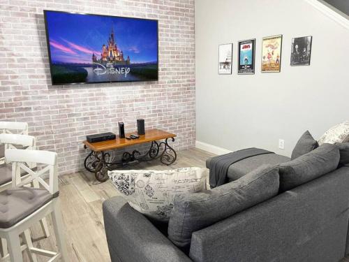 a living room with a couch and a tv on a brick wall at 3BR Townhouse Next to Disney in Orlando