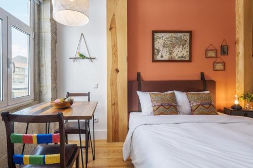 - une chambre avec des murs orange, une table et un lit dans l'établissement São Vitor Studio w/ Patio by LovelyStay, à Porto