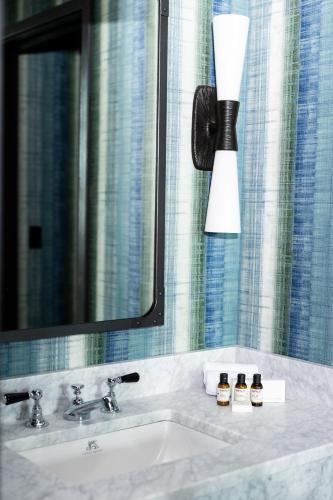 a bathroom with a sink with a mirror and a lamp at The Lincoln Hotel in Biddeford