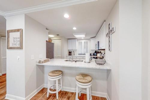 a kitchen with a sink and two stools at Turtle Sea Dunes II in Fernandina Beach