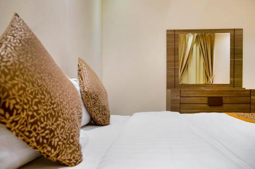 a bedroom with a bed with pillows and a mirror at Wasn Suites in Riyadh