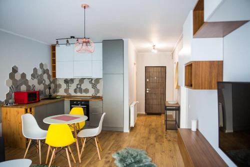 a kitchen with a table and yellow chairs in a room at YamaLux Apartments - HappyApartment - close to IuliusMall in Cluj-Napoca