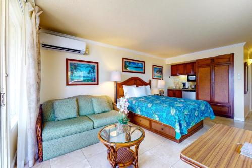 a bedroom with a bed and a couch and a table at Islander on the Beach 333 in Kapaa