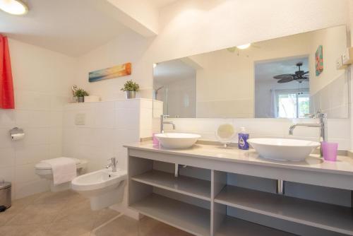 a bathroom with two sinks and a toilet and a mirror at Casa Karlina in Palm-Eagle Beach
