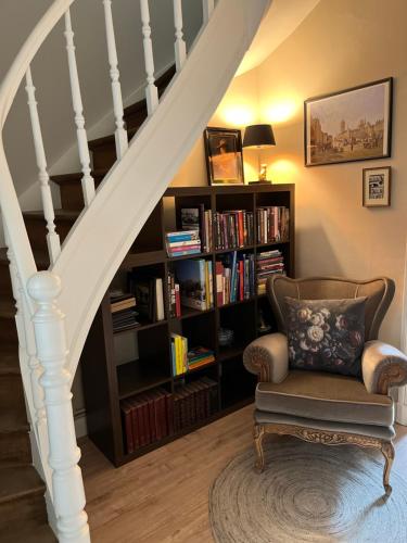 a staircase with a chair and a book shelf with books at Little gate in Ypres