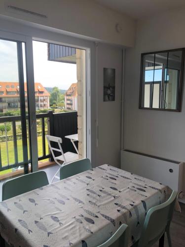 une salle à manger avec une table et des chaises et un balcon dans l'établissement Prise de vue à 2 pas de la plage, à Villers-sur-Mer